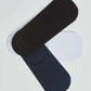 Three pairs of no show socks in black, navy, and white on a plain background