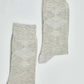 Pair of light grey argyle socks with ribbed cuffs on a plain white background