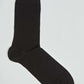 Single plain black crew sock on a white background, men's fashion accessory