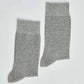 Pair of plain grey cotton socks with ribbed cuffs on a white background