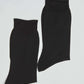 Pair of plain black ribbed ankle socks on white background