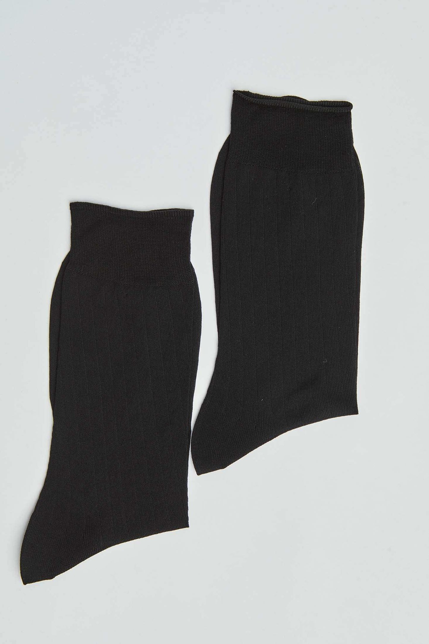 Pair of plain black ribbed ankle socks on white background