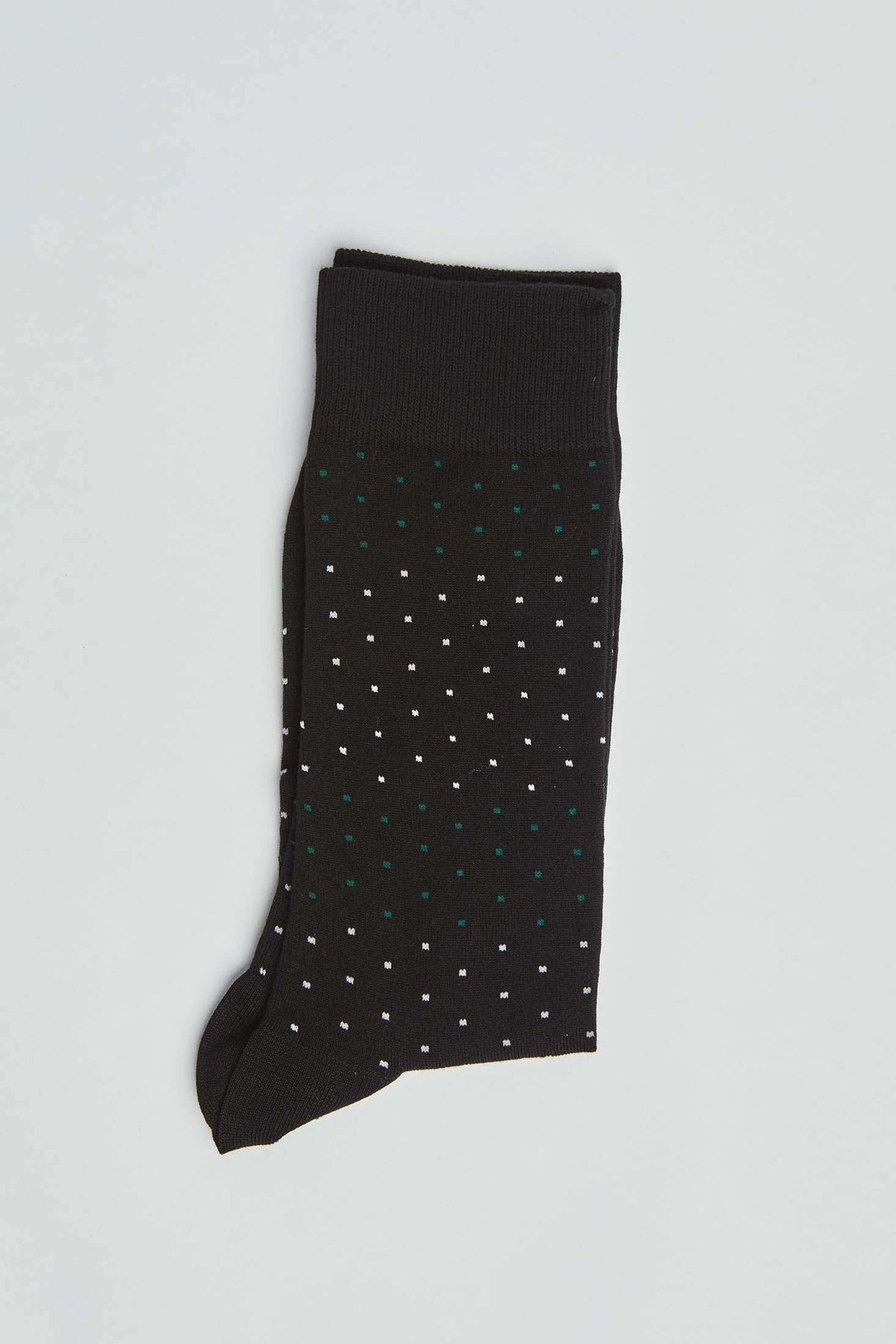 Black dress sock with small white and green polka dots on a light background