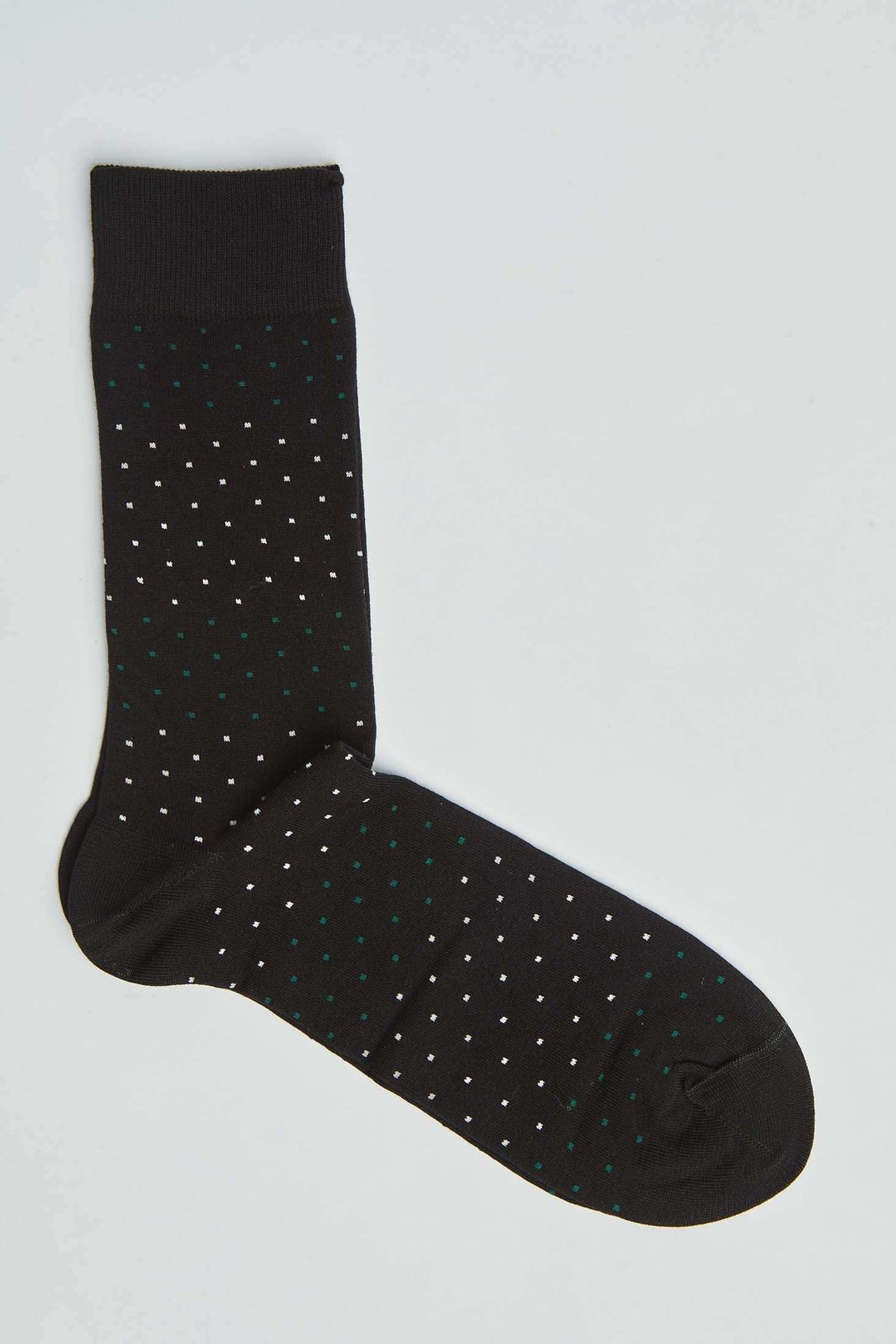 Black dress sock with white and green dot pattern on a light background