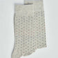 Light grey socks with small multicolored dotted pattern on a plain background