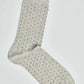 Light grey crew sock with small red, navy, and black polka dots on a white background