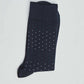 Navy blue socks with small white and green polka dots on a light background