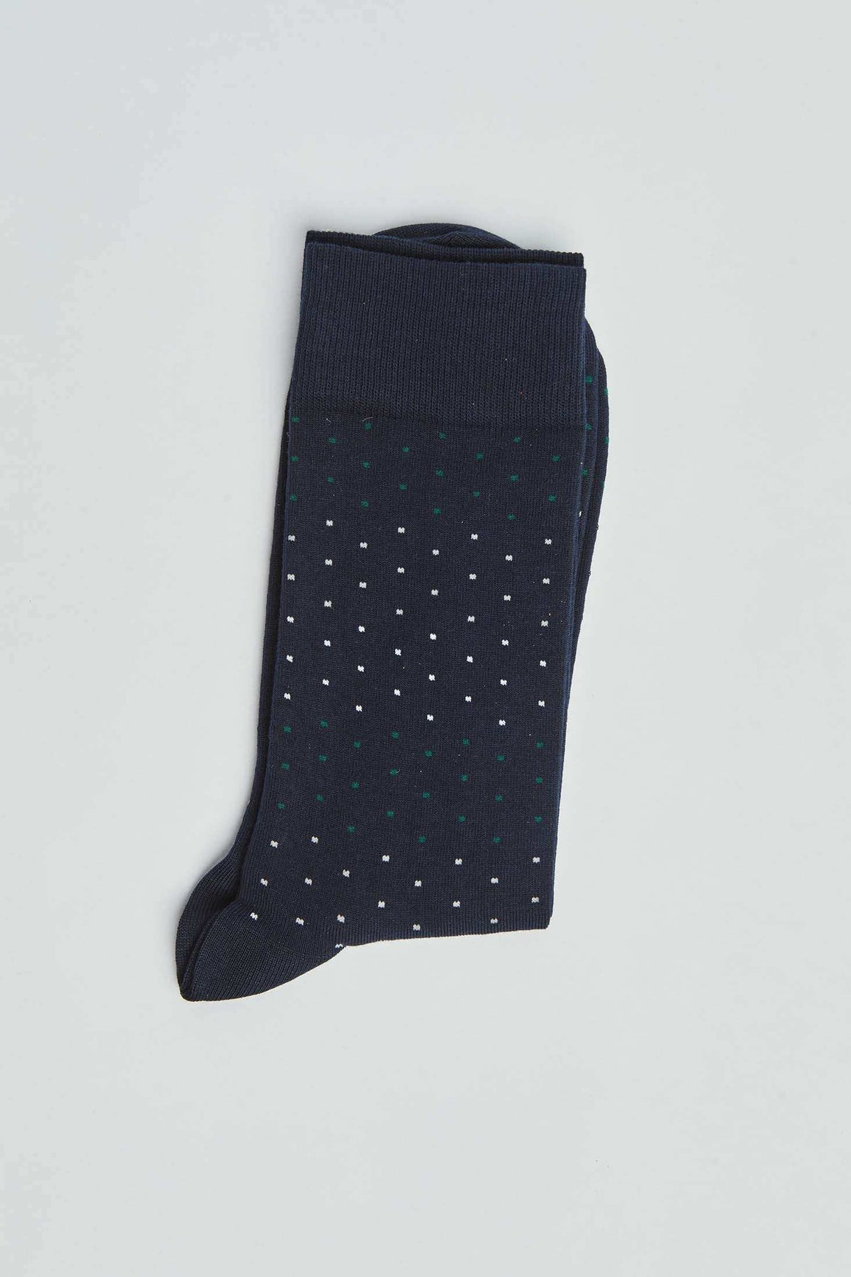 Navy blue socks with small white and green polka dots on a light background
