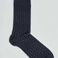 Navy blue dress sock with small white and green polka dot pattern on plain background