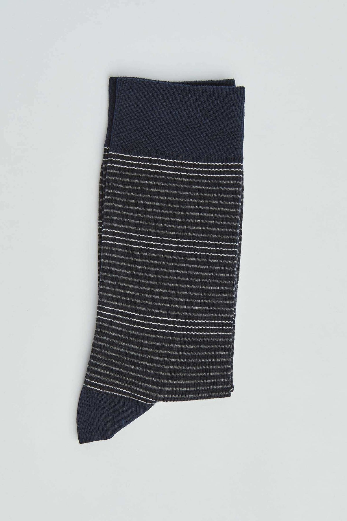 Navy blue sock with thin white and grey stripes, folded on a plain light background