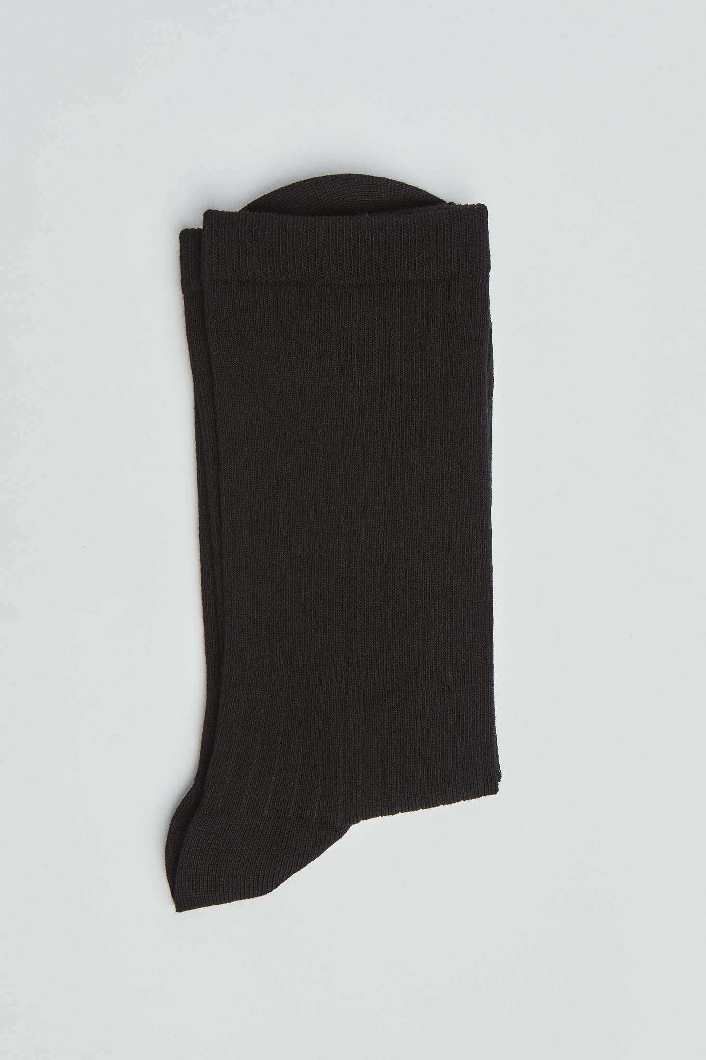 Folded black ribbed dress sock on a plain white background