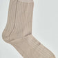 Beige ribbed crew socks with white vertical stripes on a plain background
