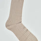 Beige ribbed dress sock with thin white stripes on white background