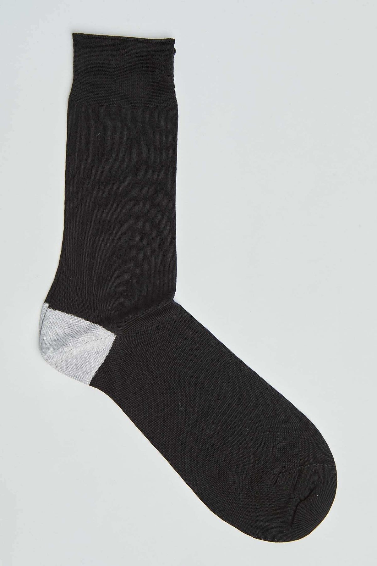 Black dress sock with contrasting white heel, flat lay on white background