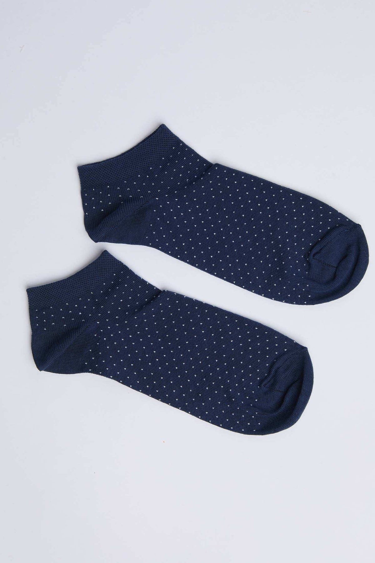 Pair of navy blue ankle socks with white polka dots on a white background