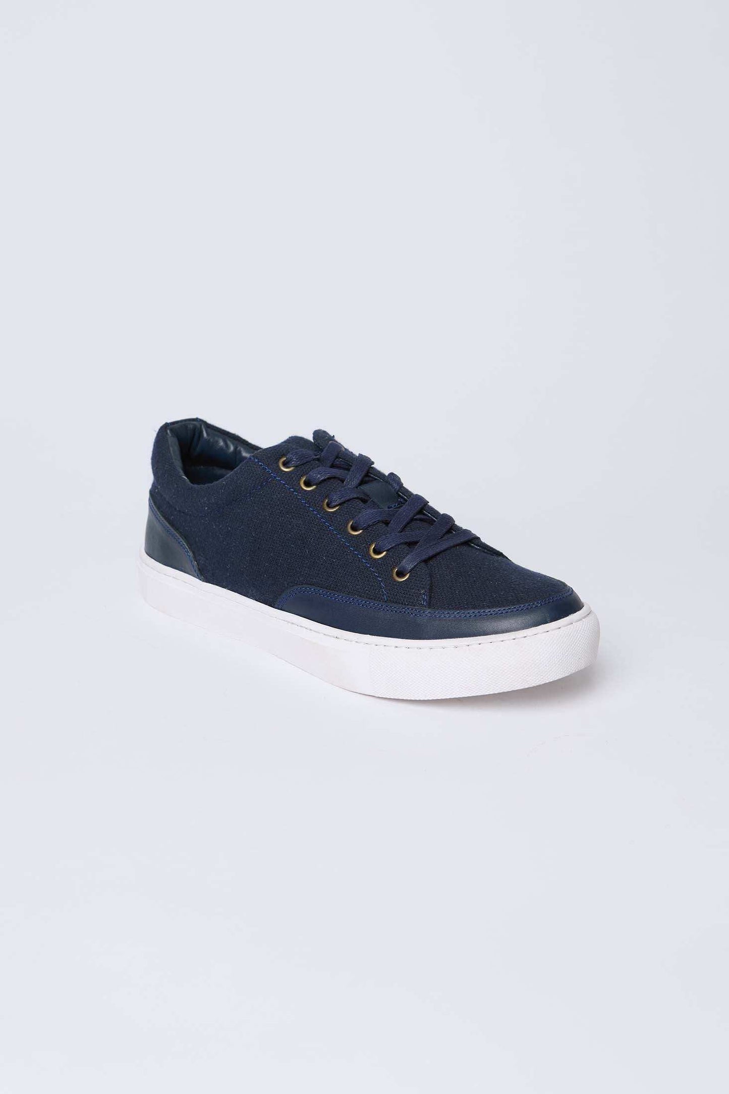 Navy blue casual sneaker with white sole and gold eyelets on a plain background