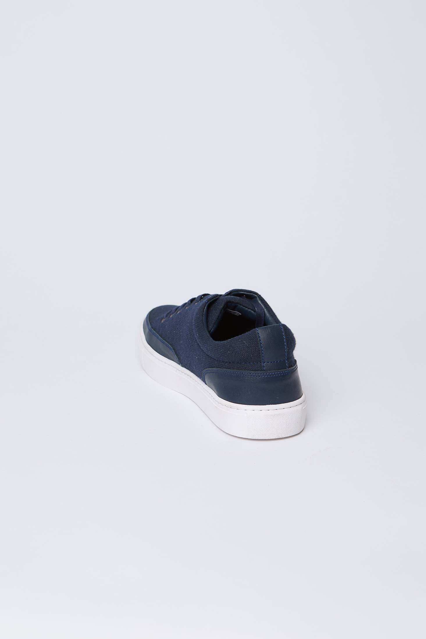 Navy blue men's casual sneaker with white sole on light background, rear angle view