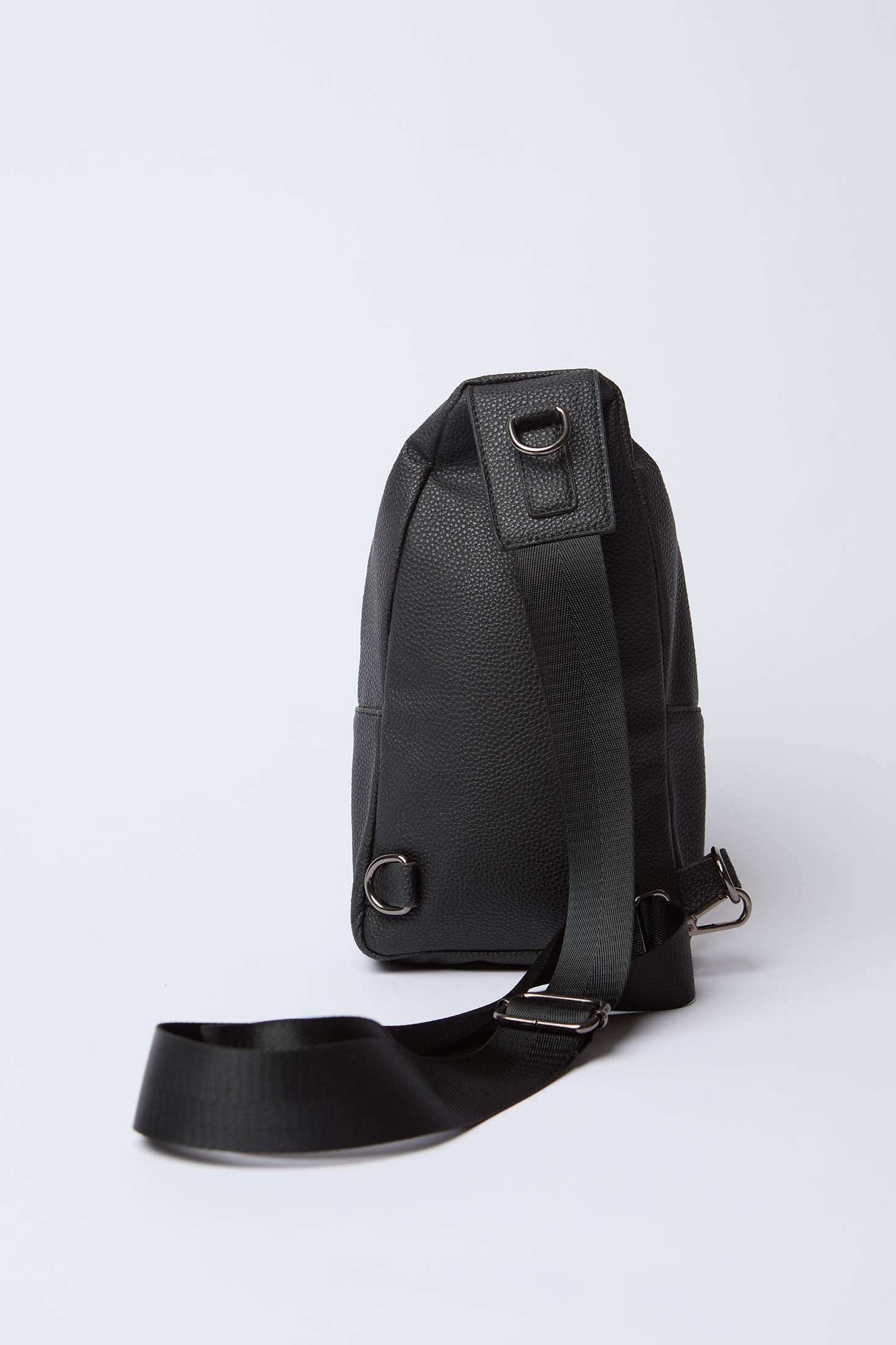 Black leather textured sling bag with adjustable strap and metallic rings on white background