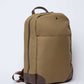 Khaki canvas backpack with brown leather trim and front pocket on white background