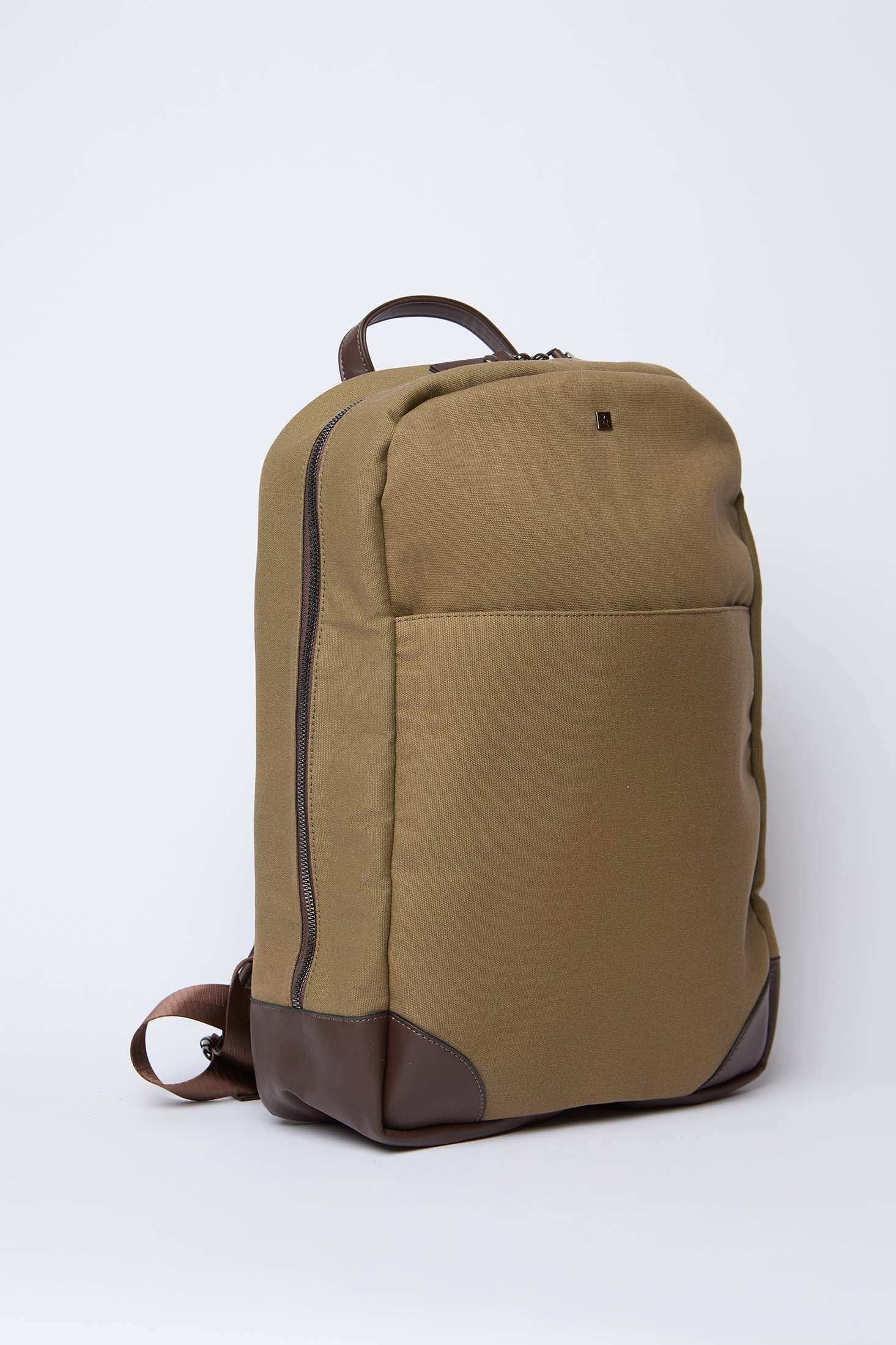 Khaki canvas backpack with brown leather trim and front pocket on white background