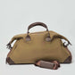 Olive green canvas duffel bag with brown leather handles and shoulder strap on white background