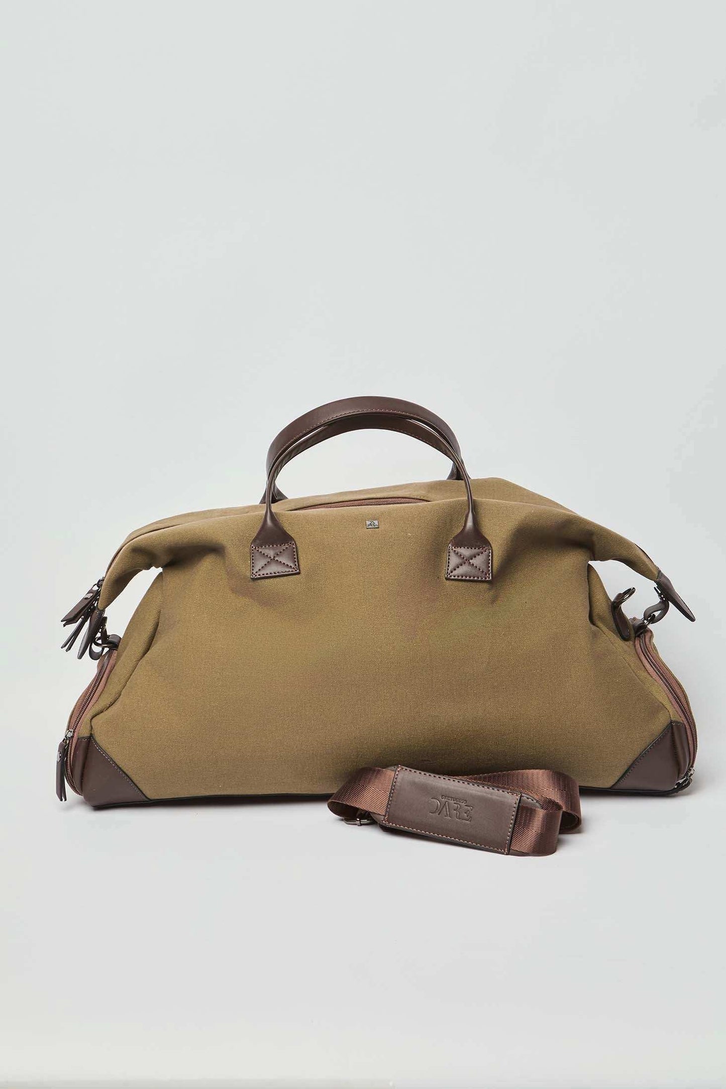 Olive green canvas duffel bag with brown leather handles and shoulder strap on white background