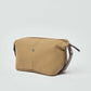 Beige canvas toiletry bag with brown leather accents and zipper on white background