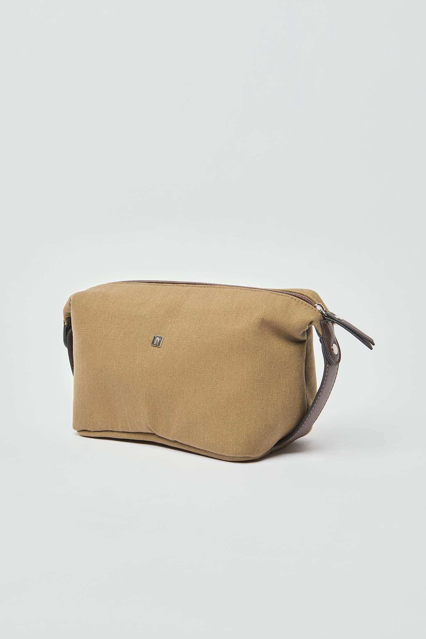Beige canvas toiletry bag with brown leather accents and zipper on white background