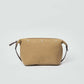 Tan canvas crossbody bag with silver rivets and leather strap on plain background