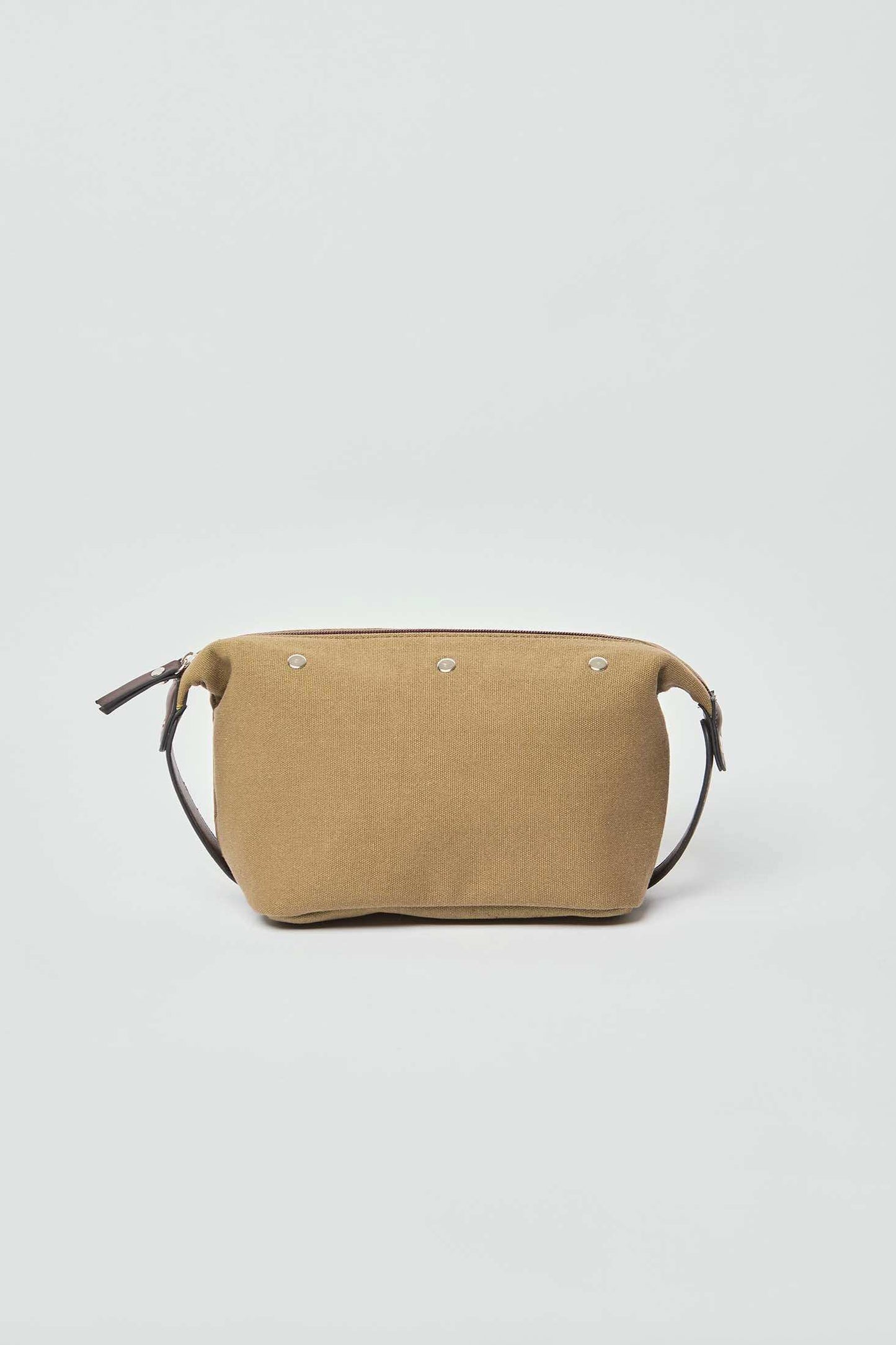 Tan canvas crossbody bag with silver rivets and leather strap on plain background