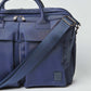 Navy blue nylon crossbody bag with double handles, front pockets, and adjustable strap