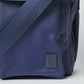 Close-up of blue crossbody bag with adjustable strap and embossed logo patch