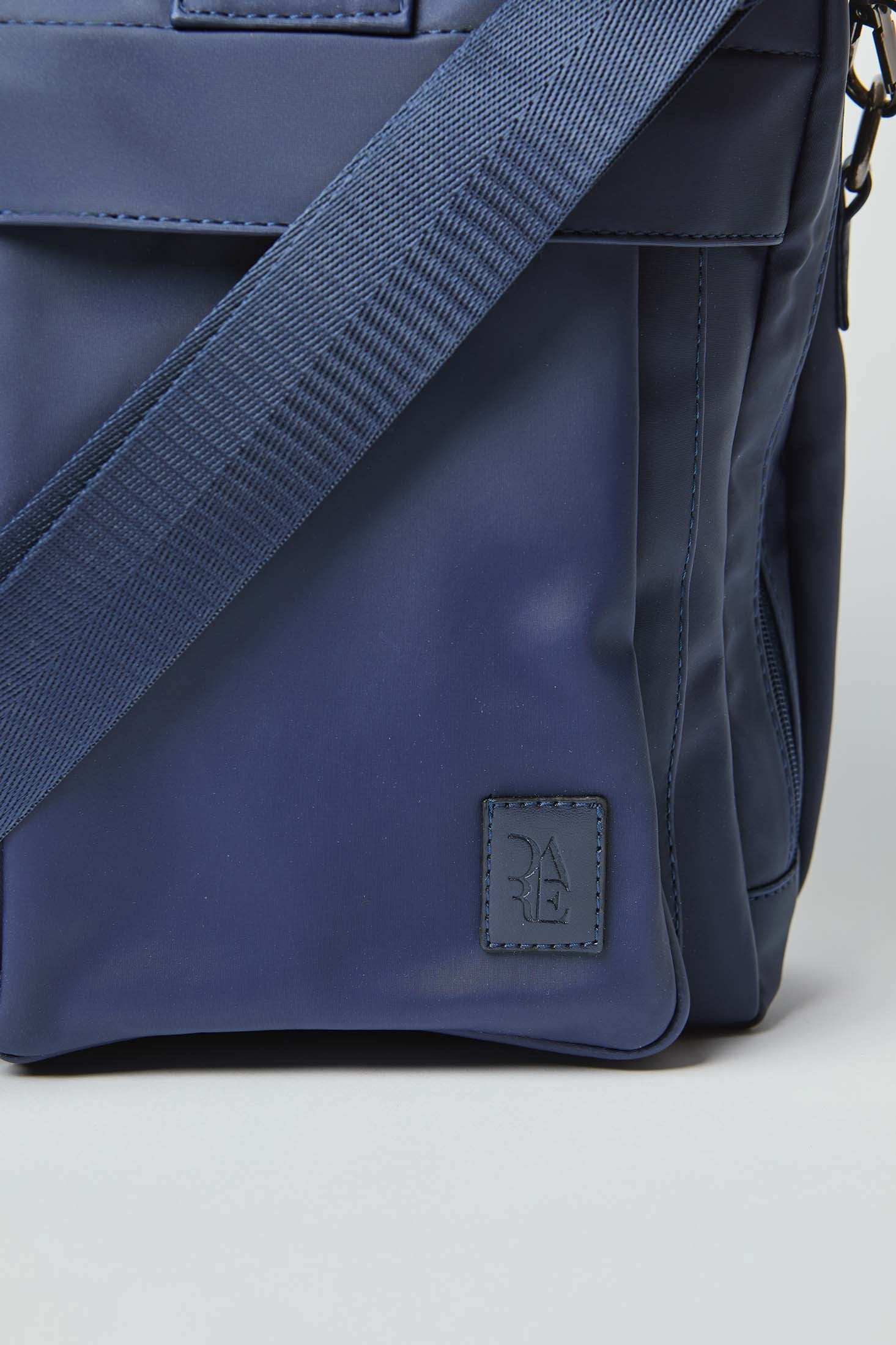 Close-up of blue crossbody bag with adjustable strap and embossed logo patch