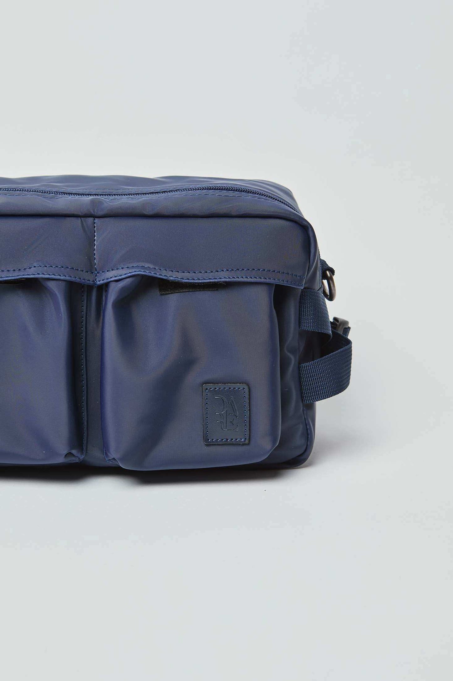 Close-up of a navy blue crossbody bag with front pockets and adjustable strap