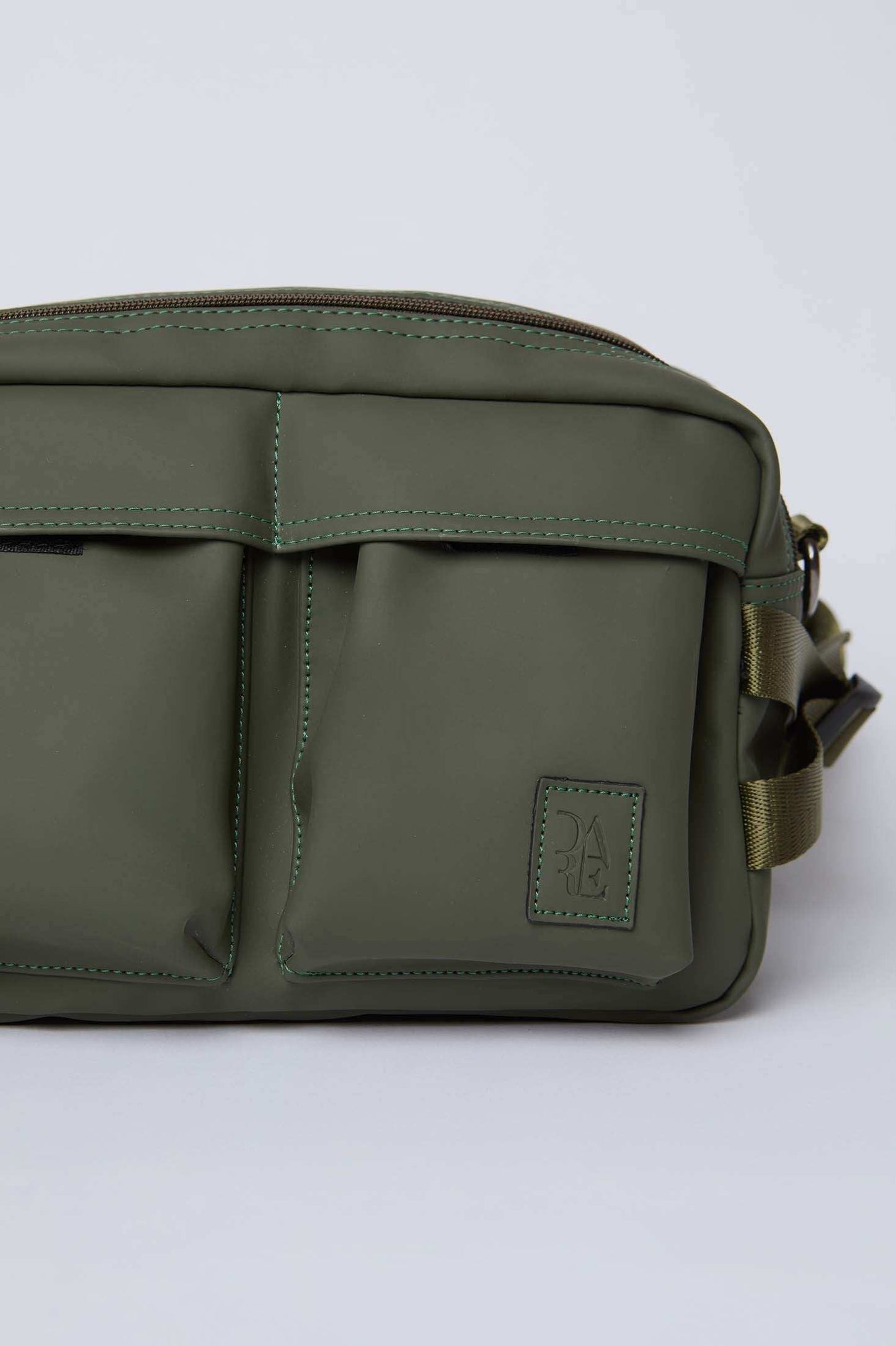 Olive green crossbody bag with dual front pockets and stitched detailing