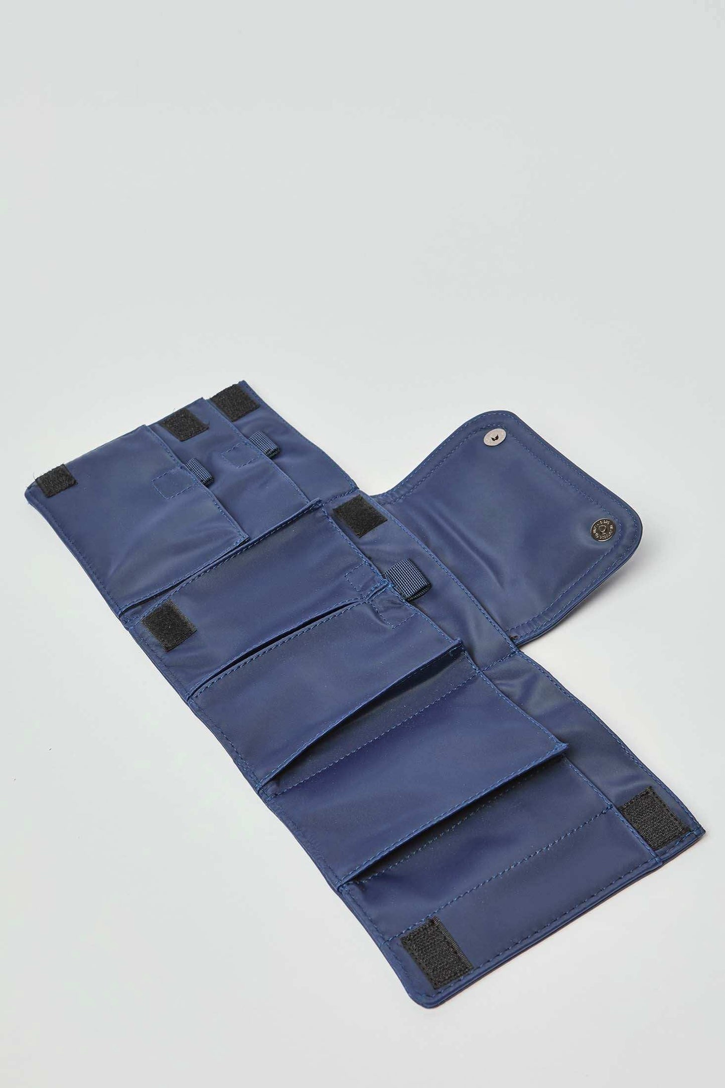 Open blue fabric organizer pouch with multiple pockets and Velcro closures on white background