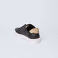 Dalydress black leather sneaker with white sole and tan heel accent on white background