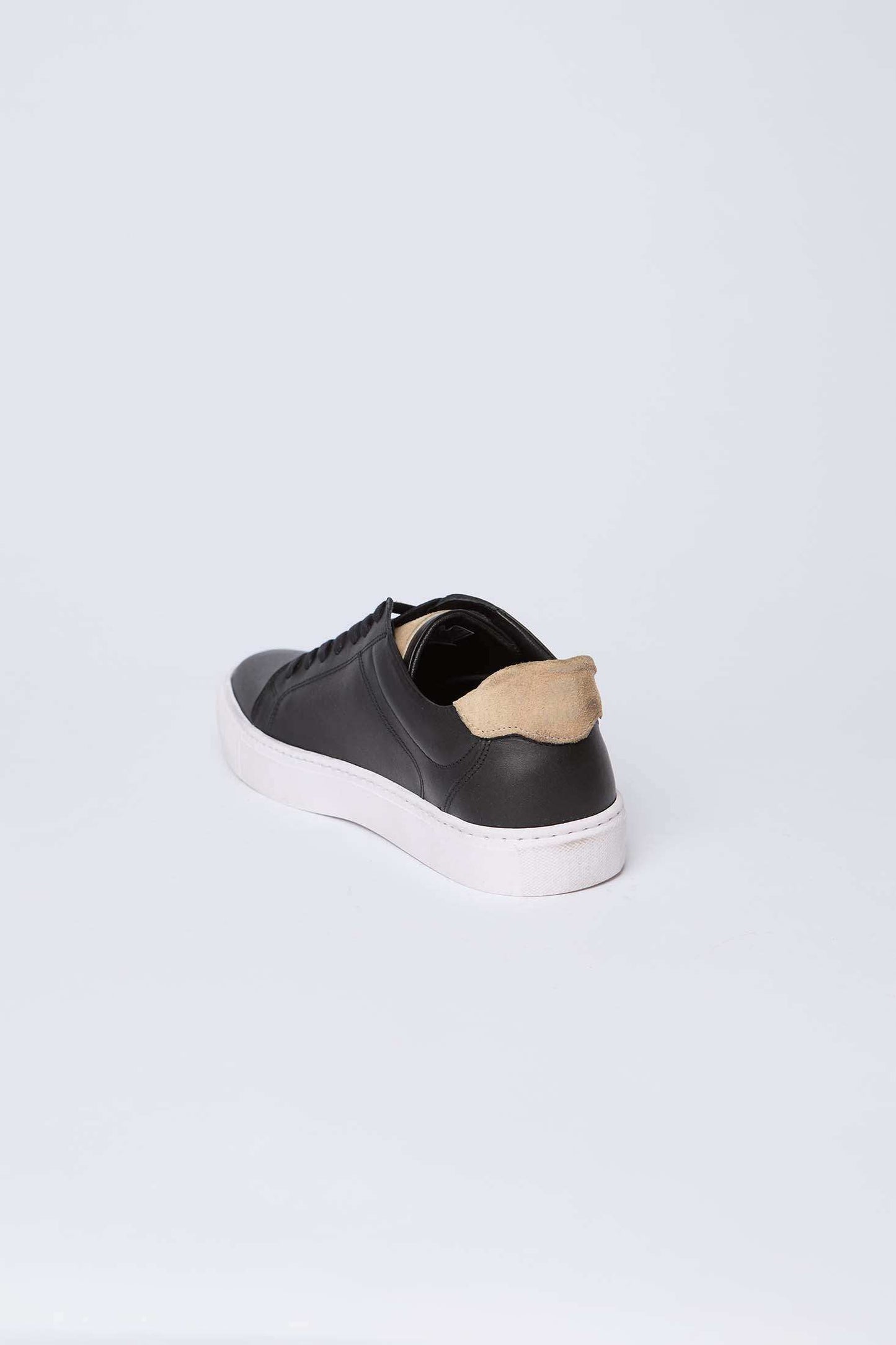 Dalydress black leather sneaker with white sole and tan heel accent on white background