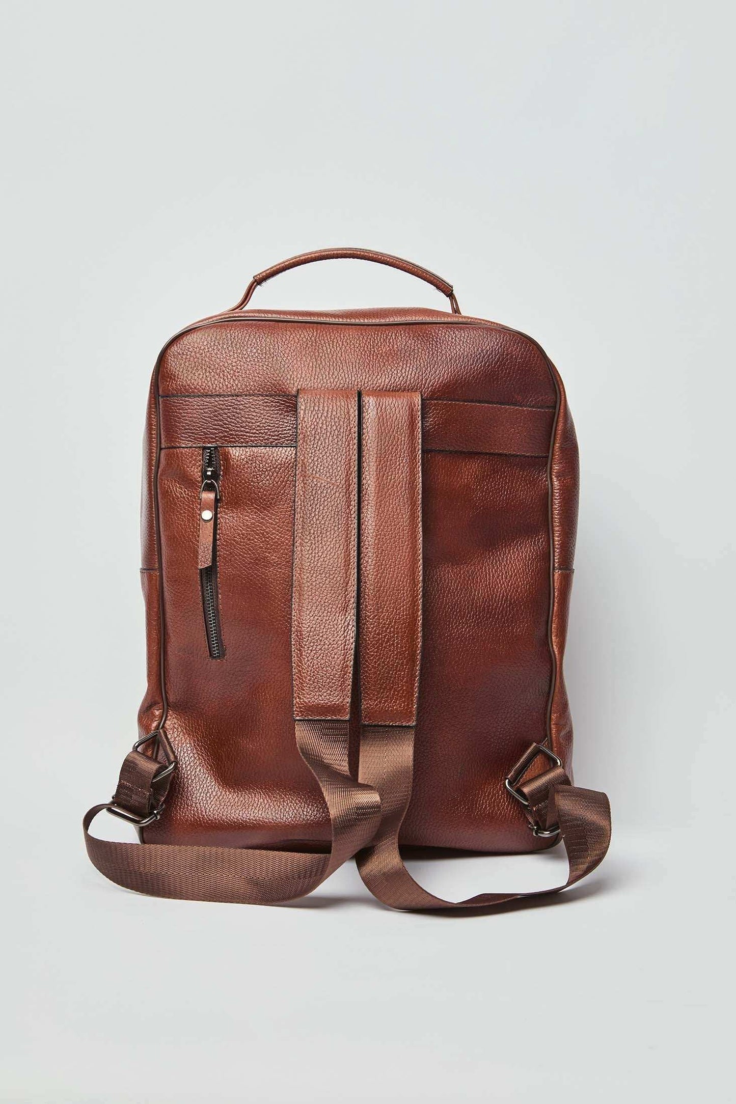 Dalydress brown leather backpack with adjustable straps and front zip pocket on white background