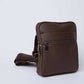 Brown leather crossbody bag with zipper pockets and adjustable strap on white background