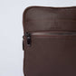 Close-up of a textured brown leather shoulder bag with zipper pocket on plain background