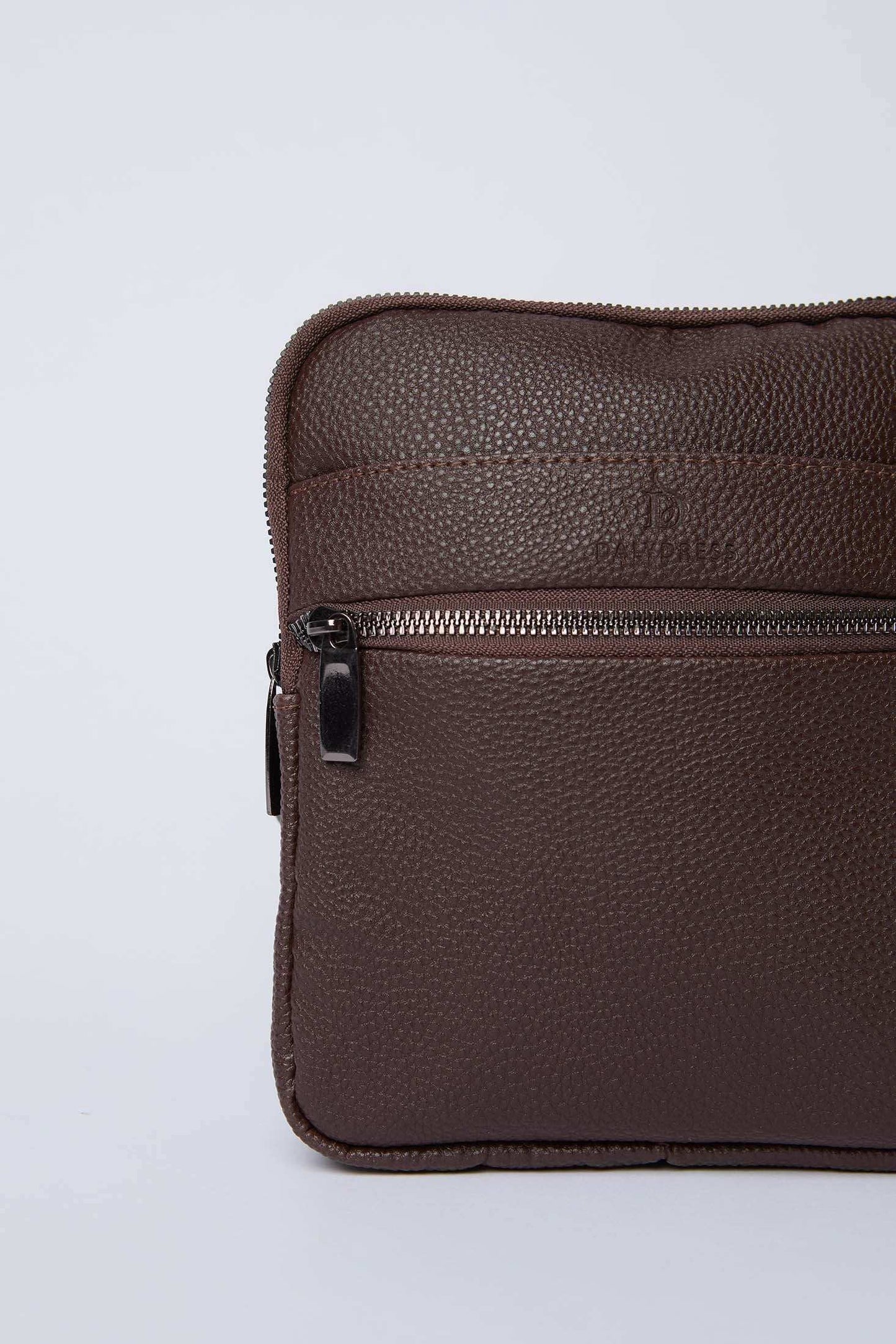 Close-up of a textured brown leather shoulder bag with zipper pocket on plain background