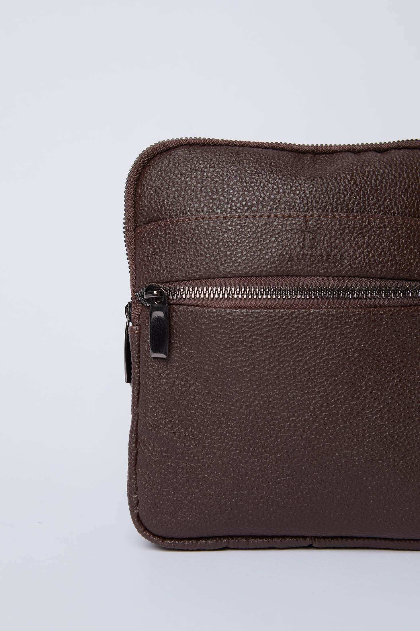 Close-up of a textured brown leather shoulder bag with zipper pocket on plain background