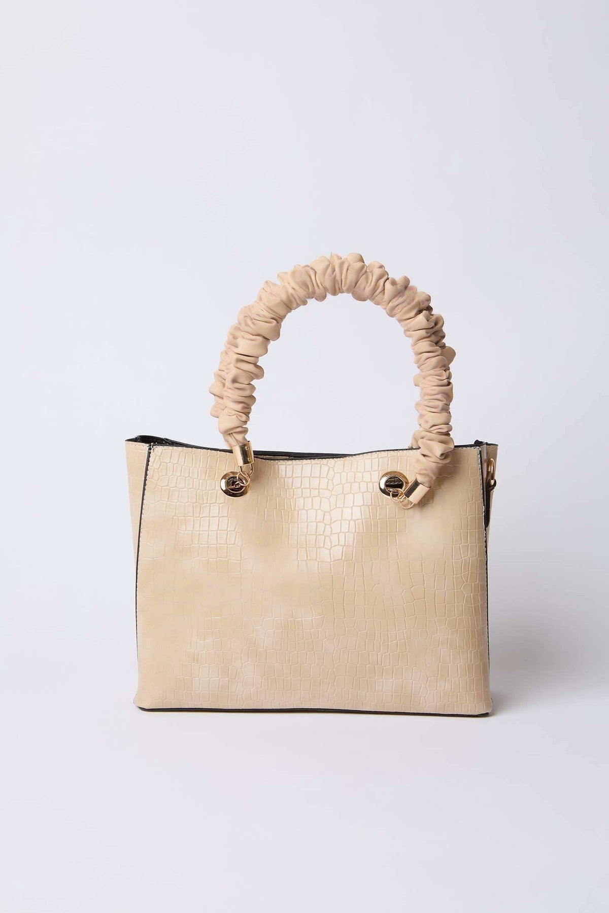 Beige textured handbag with ruched handle and gold hardware on white background