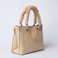 Beige textured handbag with ruched handles and gold hardware on a plain background