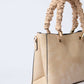 Beige textured handbag with ruched handles and gold hardware on white background