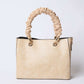 Beige textured handbag with ruched handle and gold hardware on white background