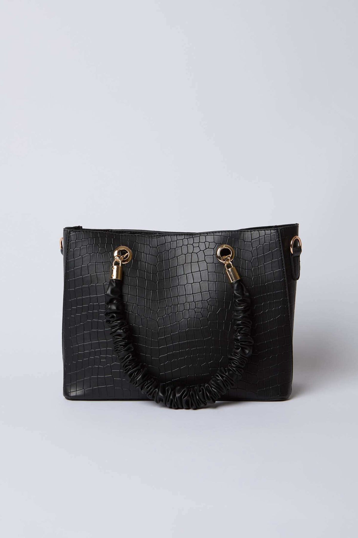 Black faux crocodile leather handbag with gold hardware and ruched handle on white background