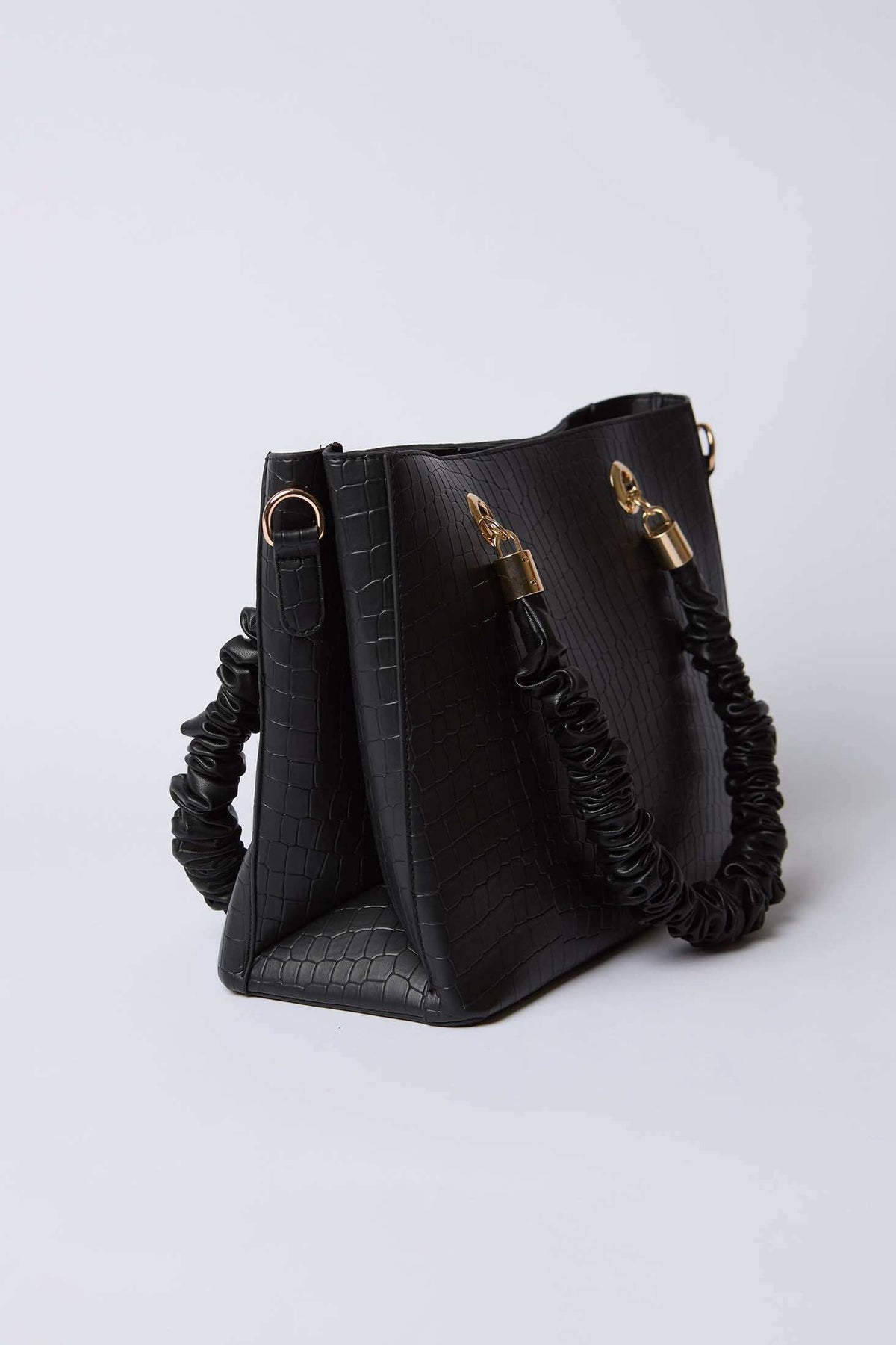 Black textured handbag with ruched handle and gold hardware on white background