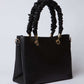 Black textured handbag with ruched handles and gold-tone hardware on white background